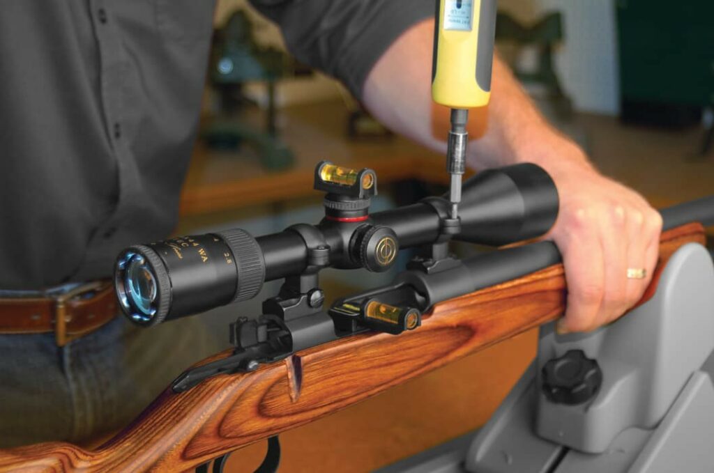 man screwing scope on rifle